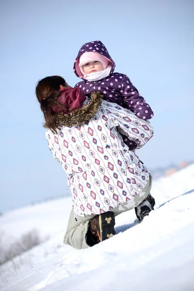 Mutter sitzt im Winter mit Kind auf Schlitten im Park — Stockfoto