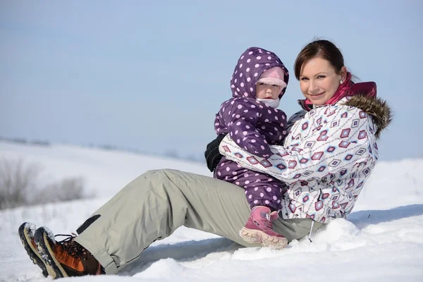 Matka siedzi na sanki w parku z dzieckiem zimą — Zdjęcie stockowe