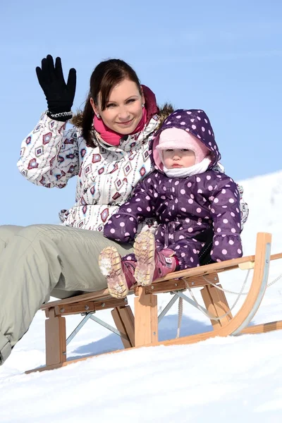Mutter sitzt im Winter mit Kind auf Schlitten im Park — Stockfoto