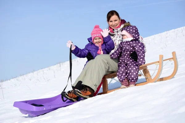 Mother sits on sled in park with children at winter — Stock Photo, Image