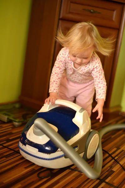 Baby with vacuum cleaner in living room — Stock Photo, Image