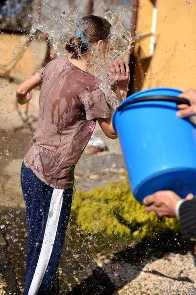 Homem derrama água em uma menina fora do balde — Fotografia de Stock