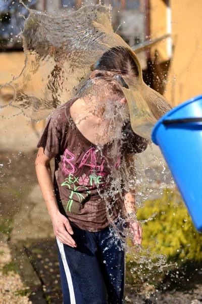 Homem derrama água em uma menina fora do balde — Fotografia de Stock