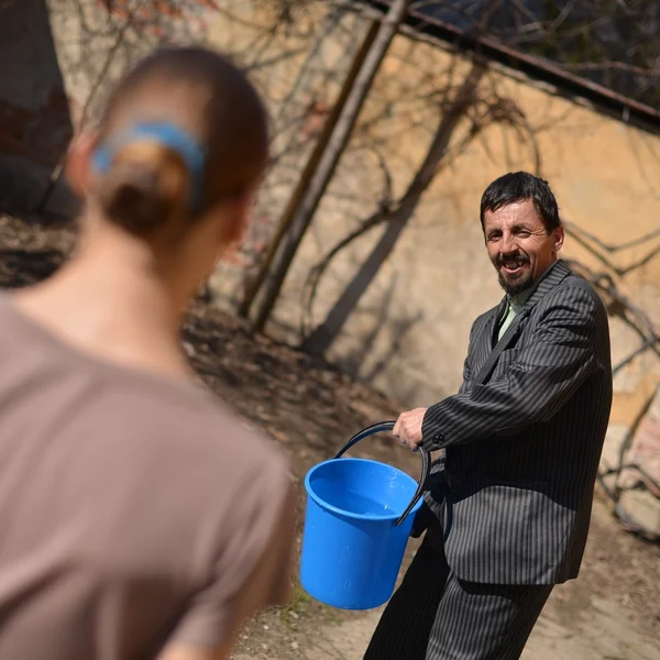 Man pours water on a girl out of the bucket — Stock Photo, Image