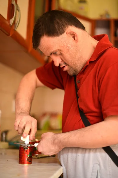 Down syndrome man cocking in the kitchen — Stock Photo, Image