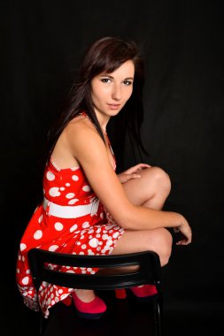 Genç bir kadın sandalyede oturuyor.