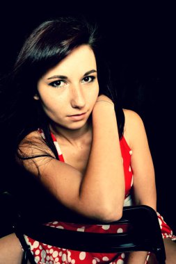 Genç bir kadın sandalyede oturuyor.