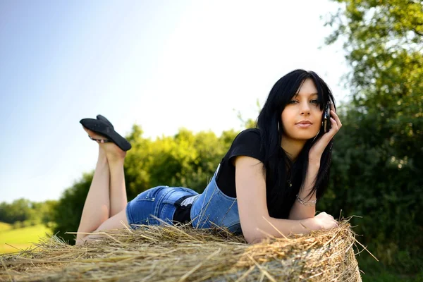 Mädchen liegt mit Handy auf Heu — Stockfoto