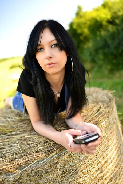Meisje liggend op hooi met mobiele telefoon — Stockfoto