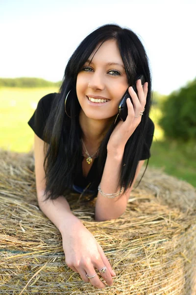 携帯電話と干し草に横たわった少女 — ストック写真