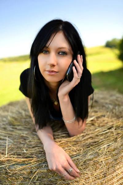 Mädchen liegt mit Handy auf Heu — Stockfoto