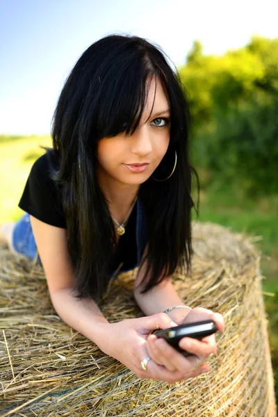 Mädchen liegt mit Handy auf Heu — Stockfoto