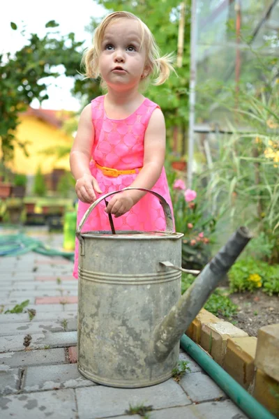 Χαριτωμένο σγουρά κορίτσι πότισμα λουλούδια στον κήπο — Φωτογραφία Αρχείου