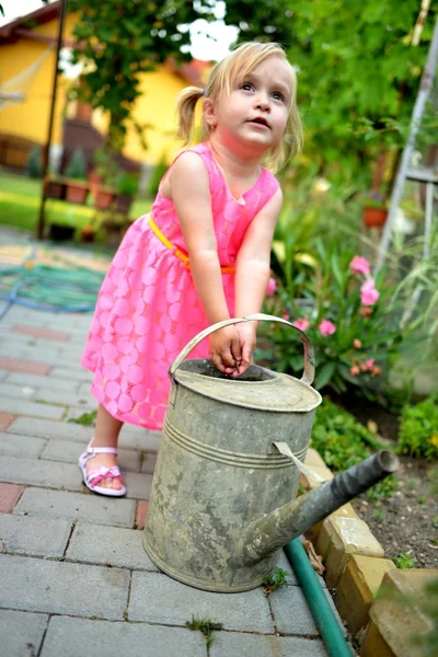 Söt lockig tjej vattna blommorna i trädgården — Stockfoto