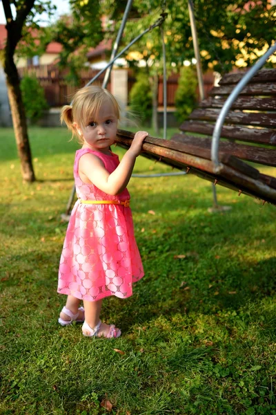 かわいい巻き毛の少女は庭の花に水をまく — ストック写真