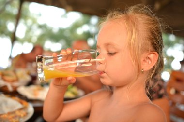 Küçük kız portakal suyu içiyor.