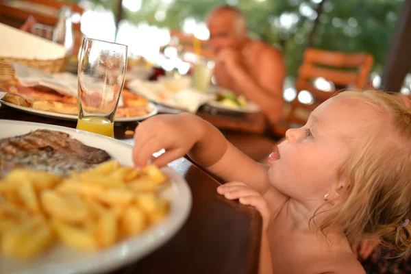 Schönes lachendes kleines Mädchen isst Pommes — Stockfoto