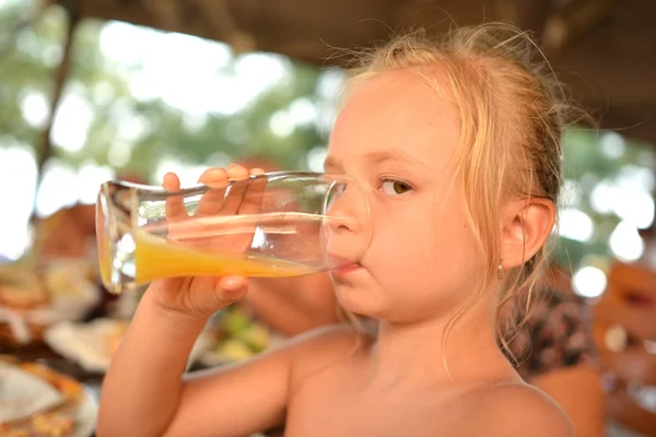 Маленька дівчинка п'є апельсиновий сік — стокове фото