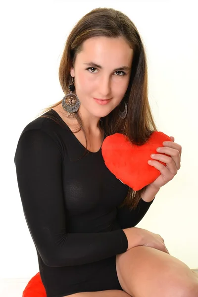 Ung kvinna med hjärtat formade röd kudde — Stockfoto