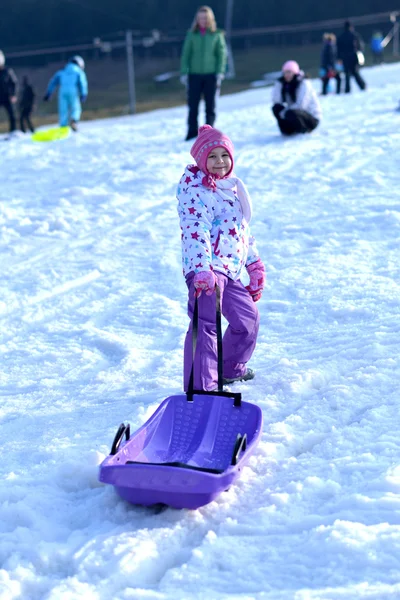 Gelukkig meisje rodelen, winter fun, sneeuw, familie rodelen — Stockfoto