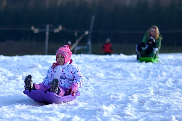 Gelukkig meisje rodelen, winter fun, sneeuw, familie rodelen — Stockfoto