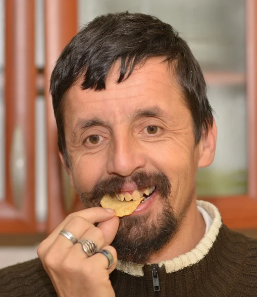 Portret van jonge brunette man eten chips — Stockfoto