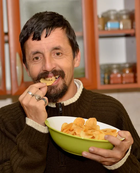 Portrait of young brunette man eating chips — Stock Photo, Image