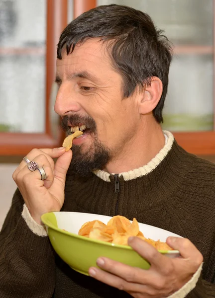 Portrait of young brunette man eating chips — Stock Photo, Image