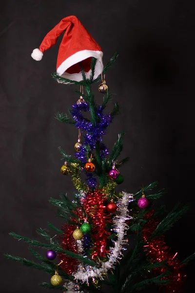 Christmas background decorated tree with santa hat on it — Zdjęcie stockowe