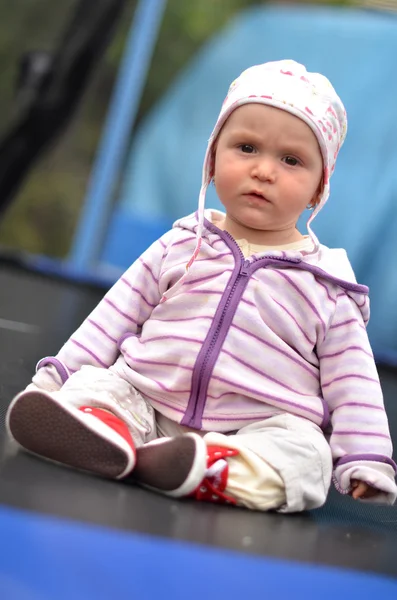 Baby flicka sitter på studsmatta — Stockfoto