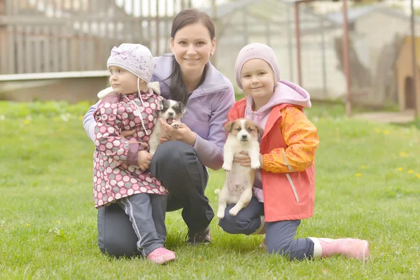 Two sisters and mother with puppies — Stock Photo, Image