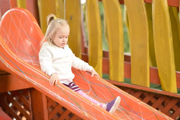 Menina na área do parque infantil slide — Fotografia de Stock