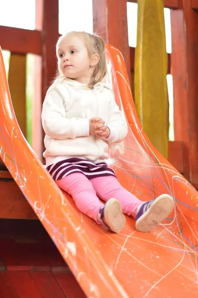 Menina na área do parque infantil slide — Fotografia de Stock