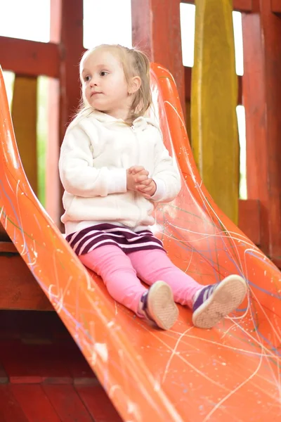 Ragazza sulla zona parco giochi scivolo — Foto Stock