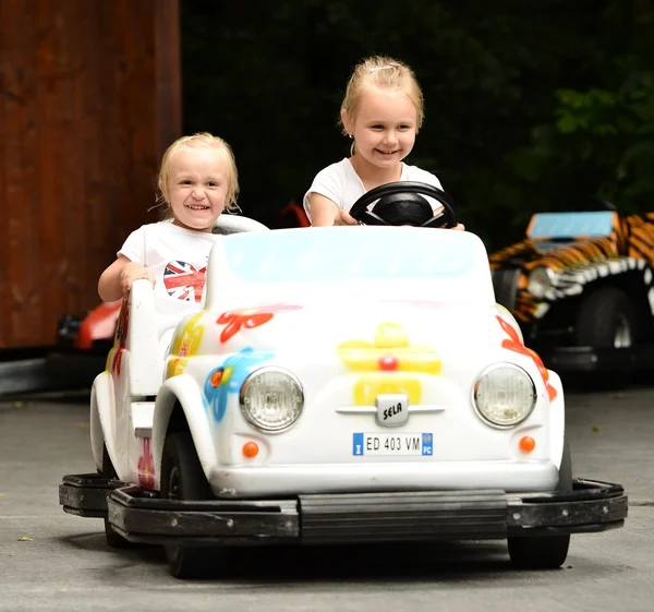 Duas meninas montando carro de brinquedo — Fotografia de Stock