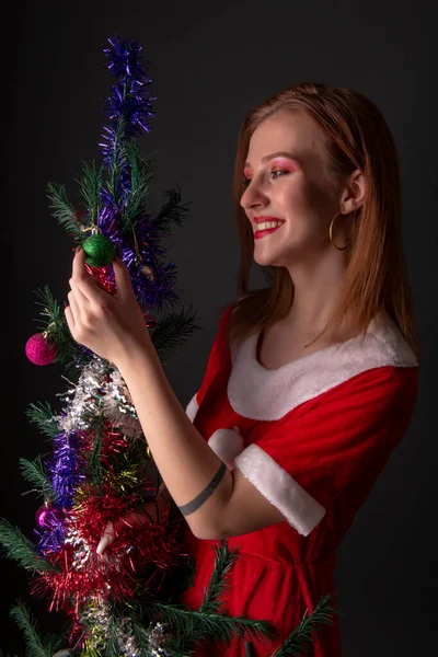 Веселая Девушка Красном Костюме Санта Клауса Позирует Украшенной Елкой Студии — стоковое фото