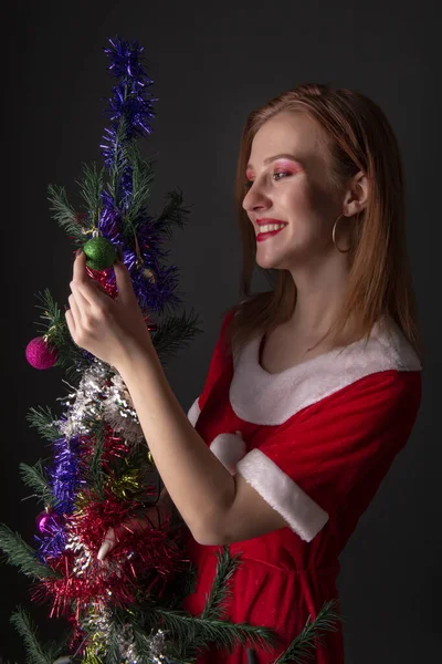 身穿红色圣诞服装 头戴装饰圣诞树的快乐女孩出现在演播室 — 图库照片