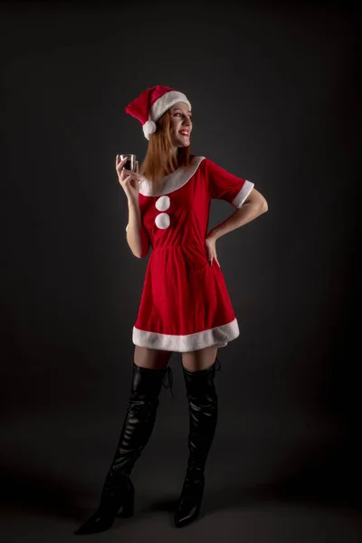 穿着红色圣诞圣塔服装 在演播室摆姿势喝酒的快乐女孩 — 图库照片