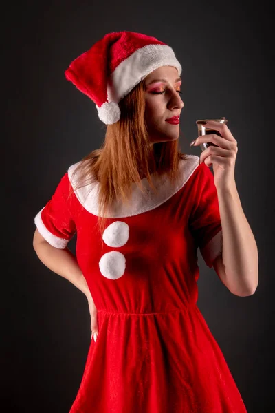 穿着红色圣诞圣塔服装 在演播室摆姿势喝酒的快乐女孩 — 图库照片