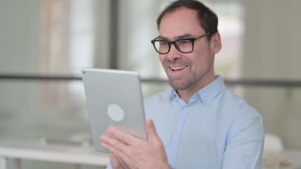 Hombre de mediana edad celebrando en la tableta en la oficina — Vídeo de stock