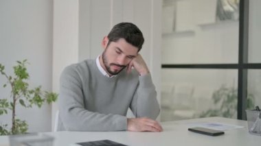 Uykulu genç adam ofiste otururken kestiriyor.