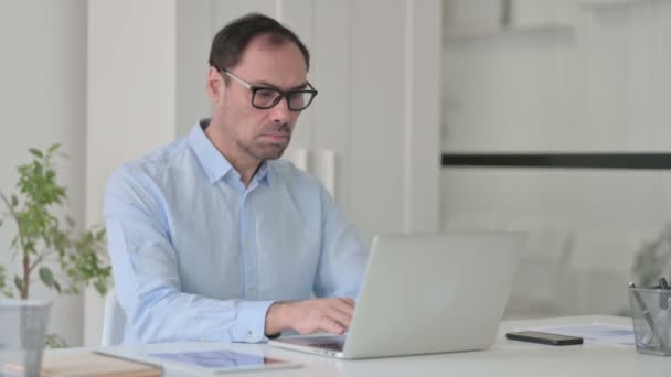 Mężczyzna w średnim wieku z laptopem wskazującym na kamerę — Wideo stockowe
