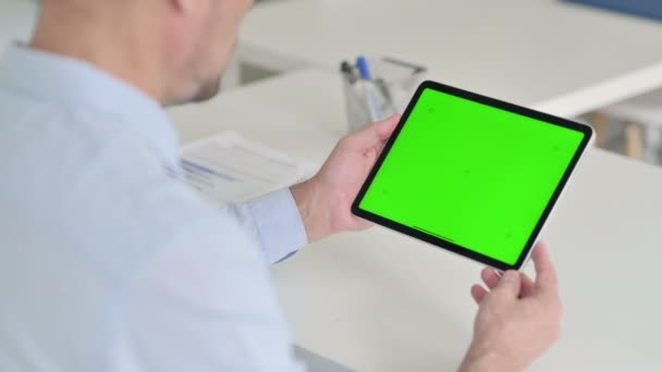 Middelbare leeftijd Man met behulp van tablet met groene chroma scherm — Stockvideo