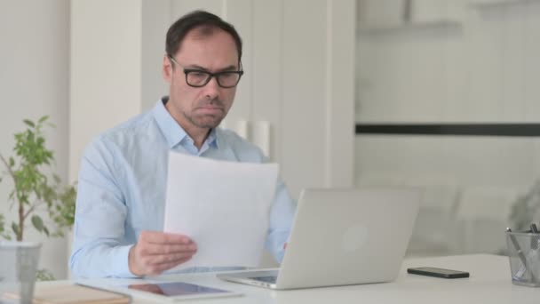 Znepokojit muže středního věku při čtení dokumentů během používání notebooku — Stock video
