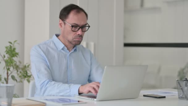 Hombre de mediana edad que tiene dolor de muñeca mientras se utiliza en el ordenador portátil — Vídeo de stock