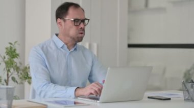 Ofiste dizüstü bilgisayar kullanırken orta yaşlı adam öksürüyor 