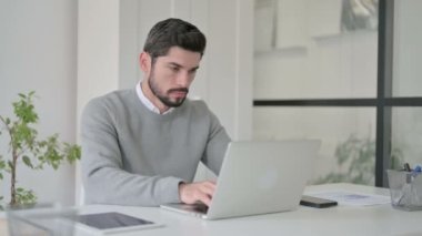 Ofiste dizüstü bilgisayar kullanırken öksüren genç adam. 