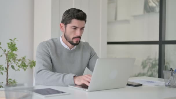 Молодой человек с болями в шее во время использования ноутбука в офисе — стоковое видео