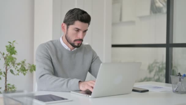 Ofiste dizüstü bilgisayar kullanırken öksüren genç adam. — Stok video