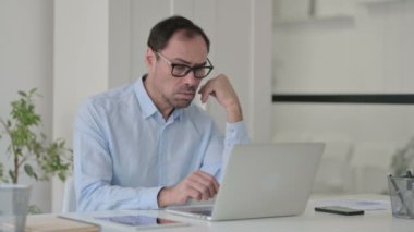 Ofiste dizüstü bilgisayar kullanırken uyuyan orta yaşlı adam, şekerleme.